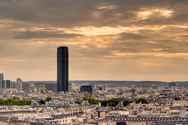 Paris skyline with Maine-Montparnasse Tower, France. View of Tour Montparnasse on sunset sky background. Dark Montparnasse Tower rises above buildings. Panorama of city with Montparnasse